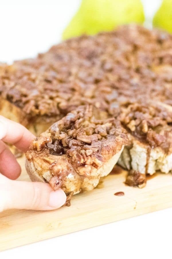 pear stuffed pecan sticky buns in  a hand with a focus.