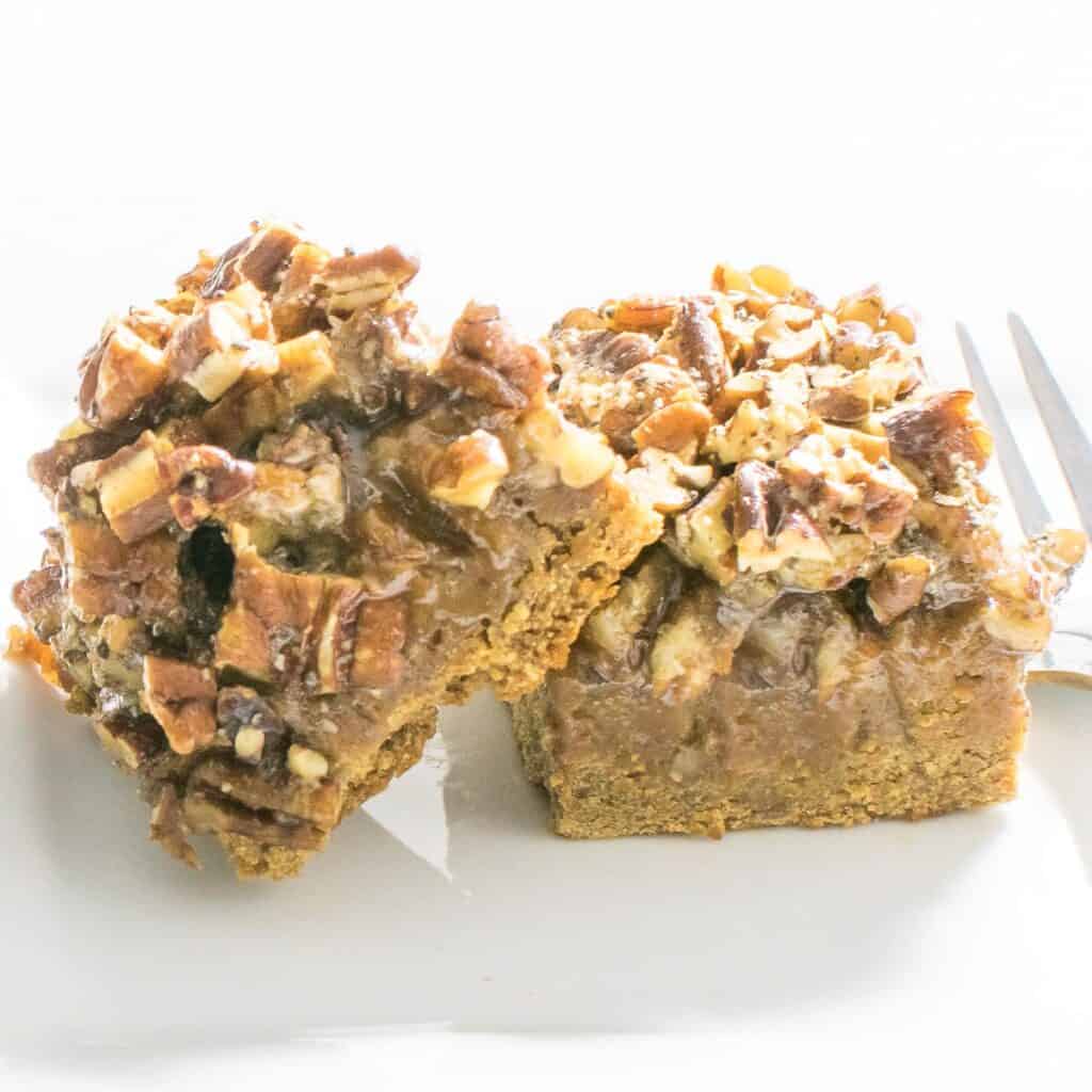 A front view of squared pecan pie bars on a serving plate.