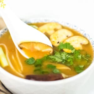 A spoon dipping in instant pot tom yum soup recipe.