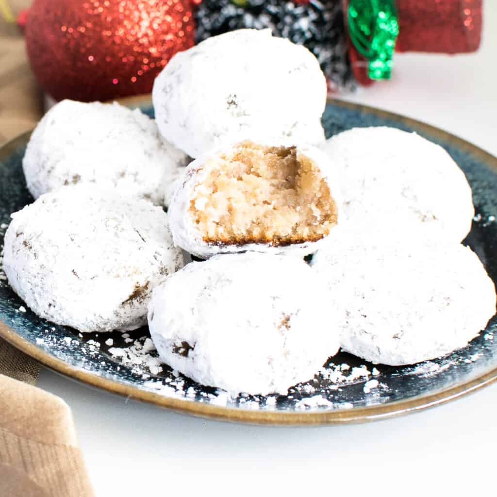 A stack of snowball cookies with half eaten cookie at the top.