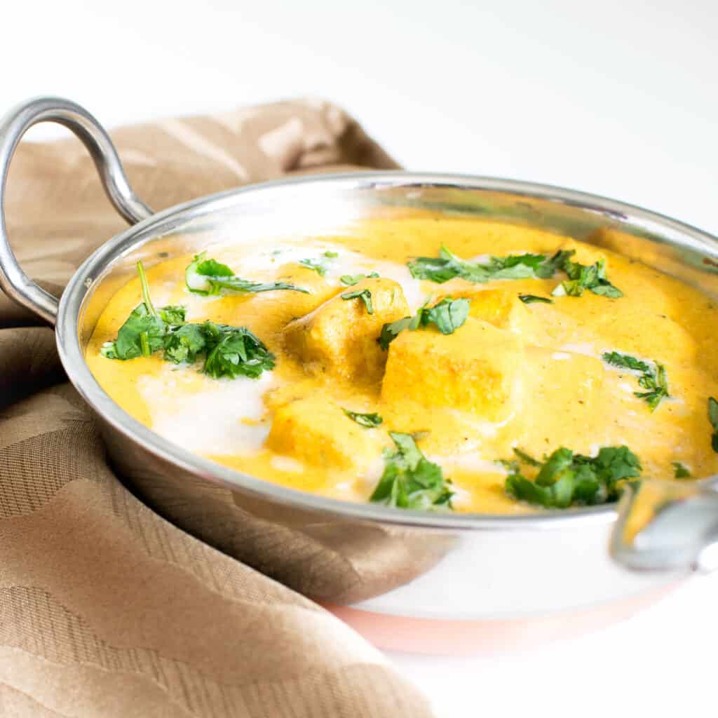 Butter Tofu in kadhai with a serving spoon.