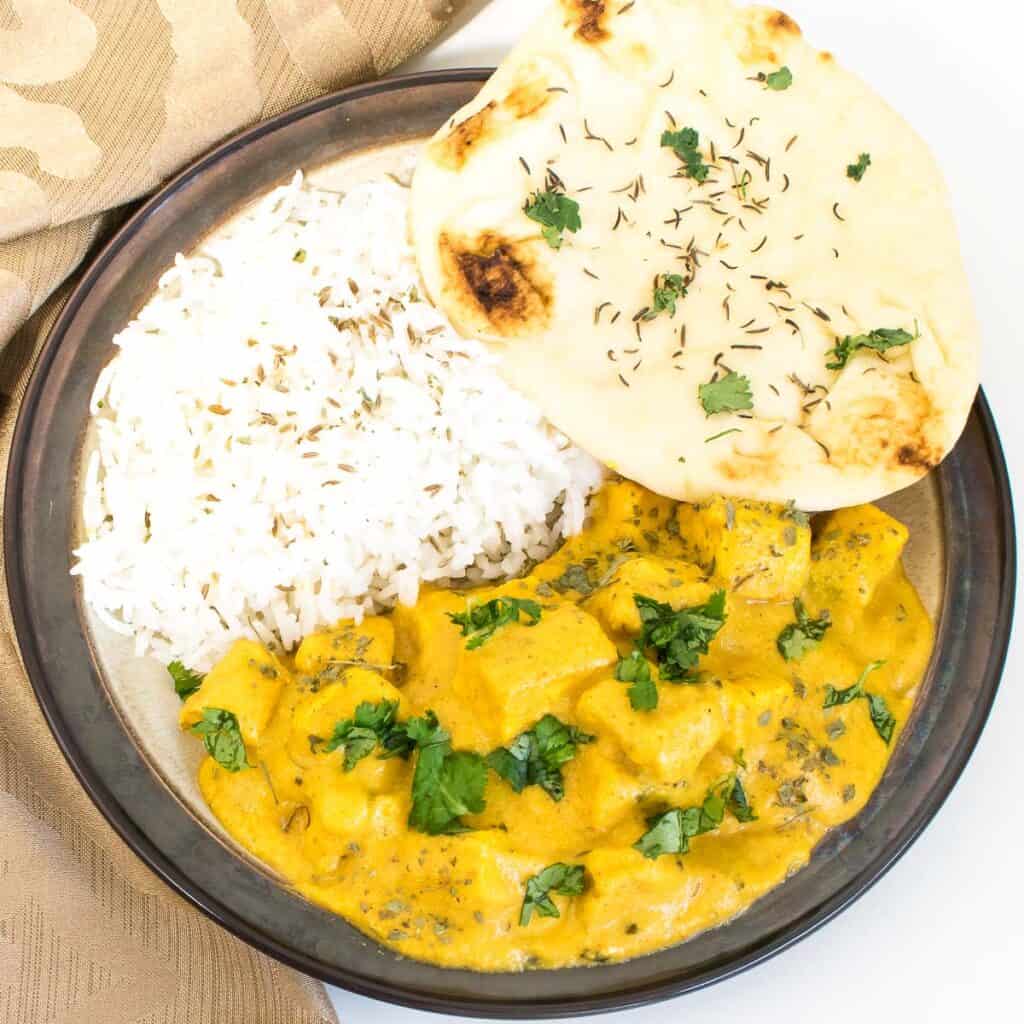 top view of served butter tofu with rice and naan.