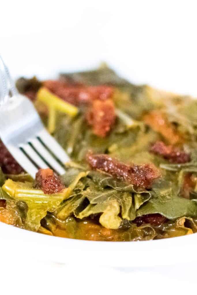 a fork digging into vegan collard greens.