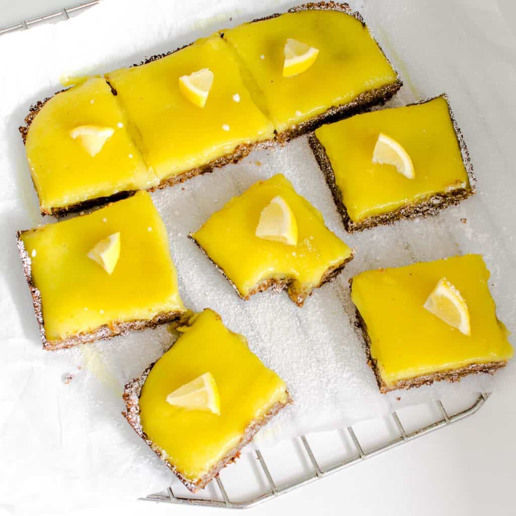 top view of sliced vegan lemon bars spread on a parchment paper with a half eaten slice in the middle.