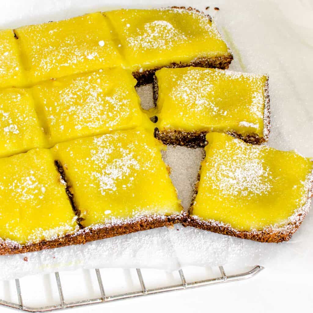 a 45 degree angle view of vegan lemon bars on a parchment paper.
