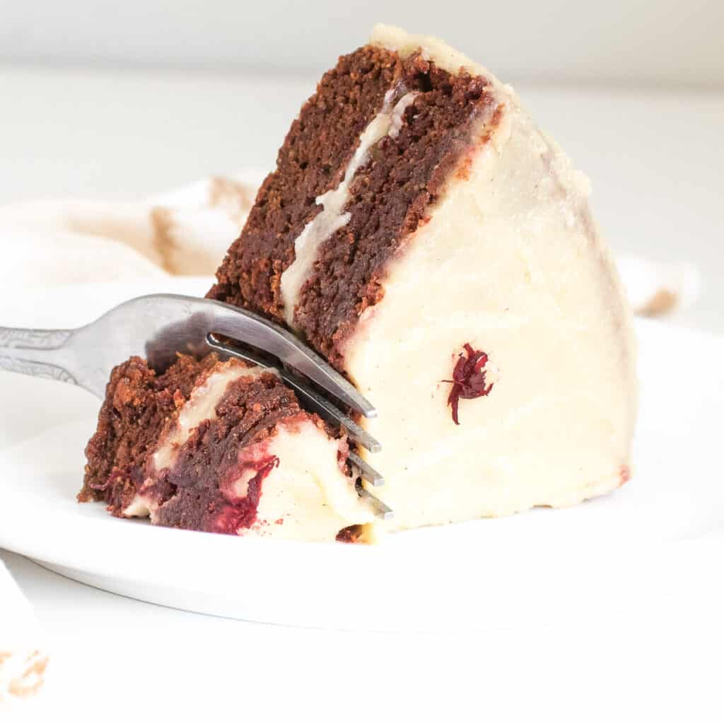 a fork digging into a slice of vegan red velvet cake.