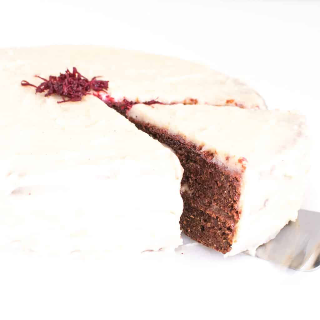 A slice coming out of the entire vegan red velvet cake.