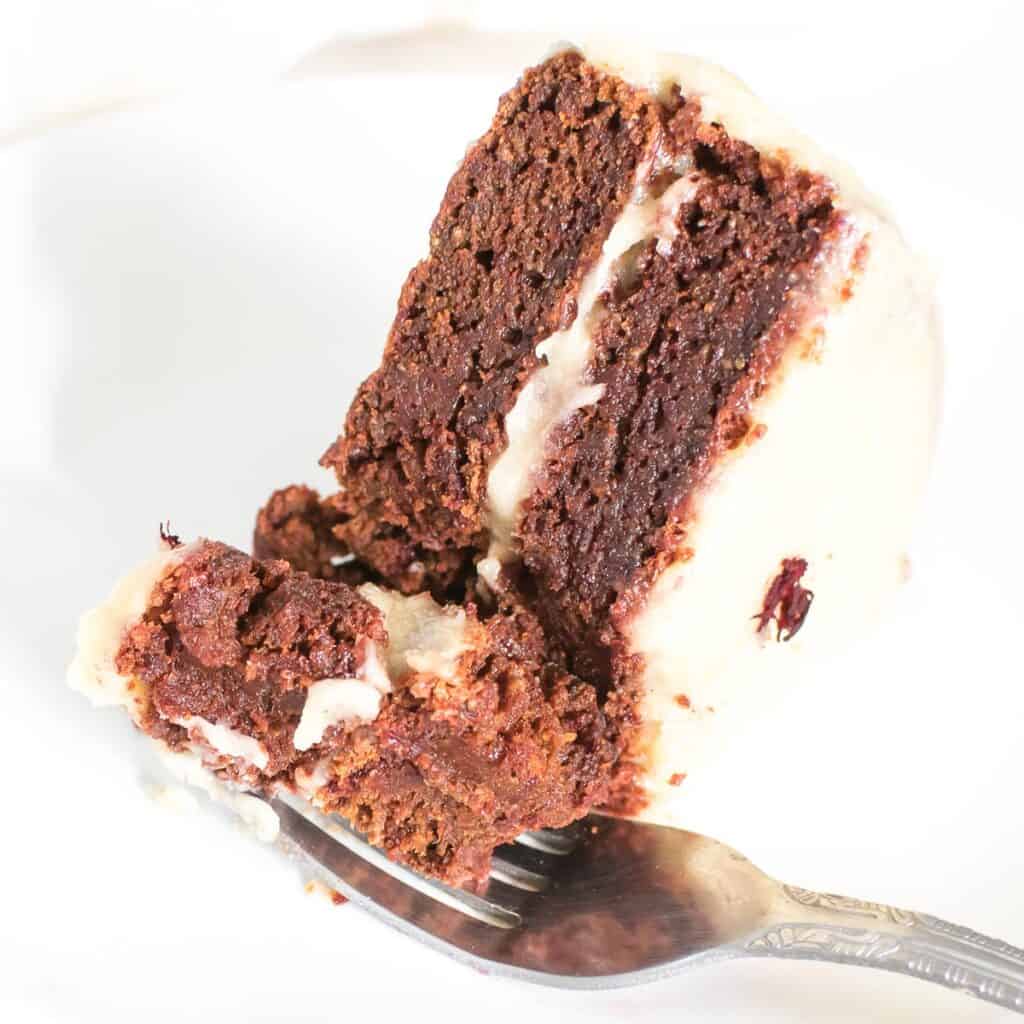 a fork picking a bite of the sliced vegan red velvet cake.