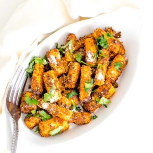 top view of air fryer carrots with garnishes in a serving plate.