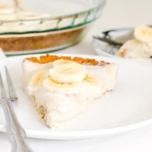 a front view of vegan banana cream pie slice in the serving plate along with the whole table spread.