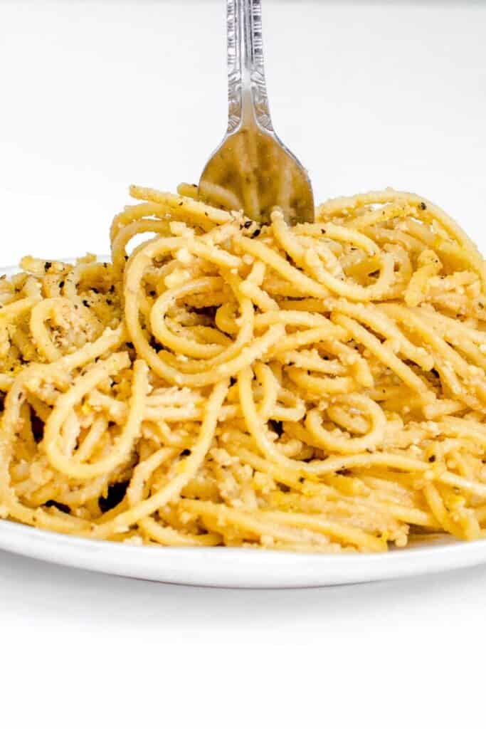 a fork digging into heaped vegan cacio e pepe.