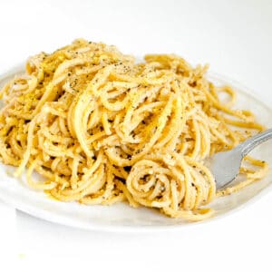 a side view of a fork rolled in vegan cacio e pepe.
