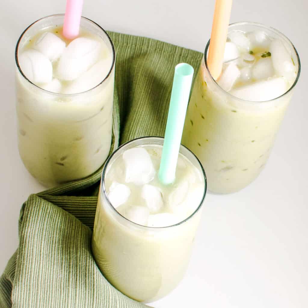 top view of serving glasses filled with iced matcha latte along with straws.