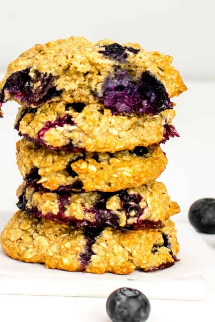 a tall stack of blueberry oatmeal cookies with a half eaten one at the top. 