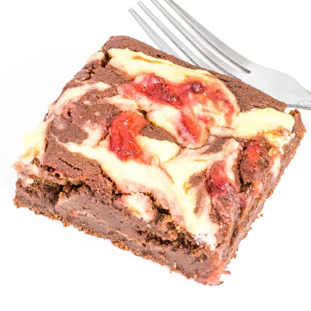 a close up view of a slice of strawberry cheesecake brownies.