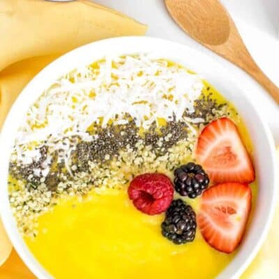 top view of mango smoothie bowl with fruits at the backdrop.