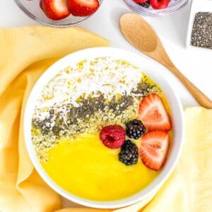top view of mango smoothie bowl with fruits at the backdrop.