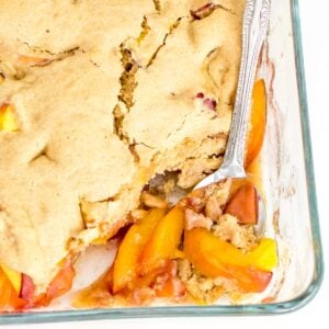 a close up view of vegan peach cobbler in the baking dish.
