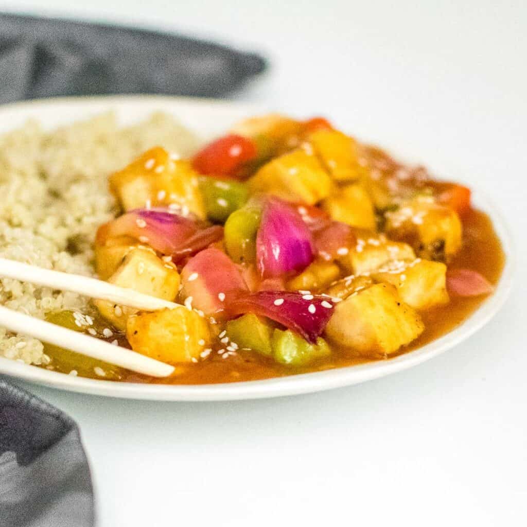 a chopstick picking up sweet and sour tofu.