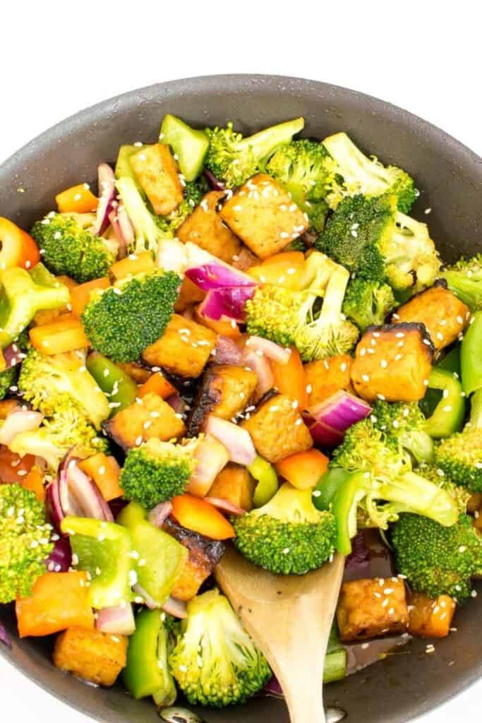 a close up view of tempeh stir fry with a spatula.