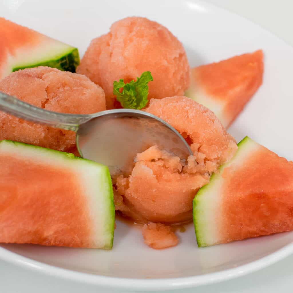 a spoon digging through watermelon ice cream.