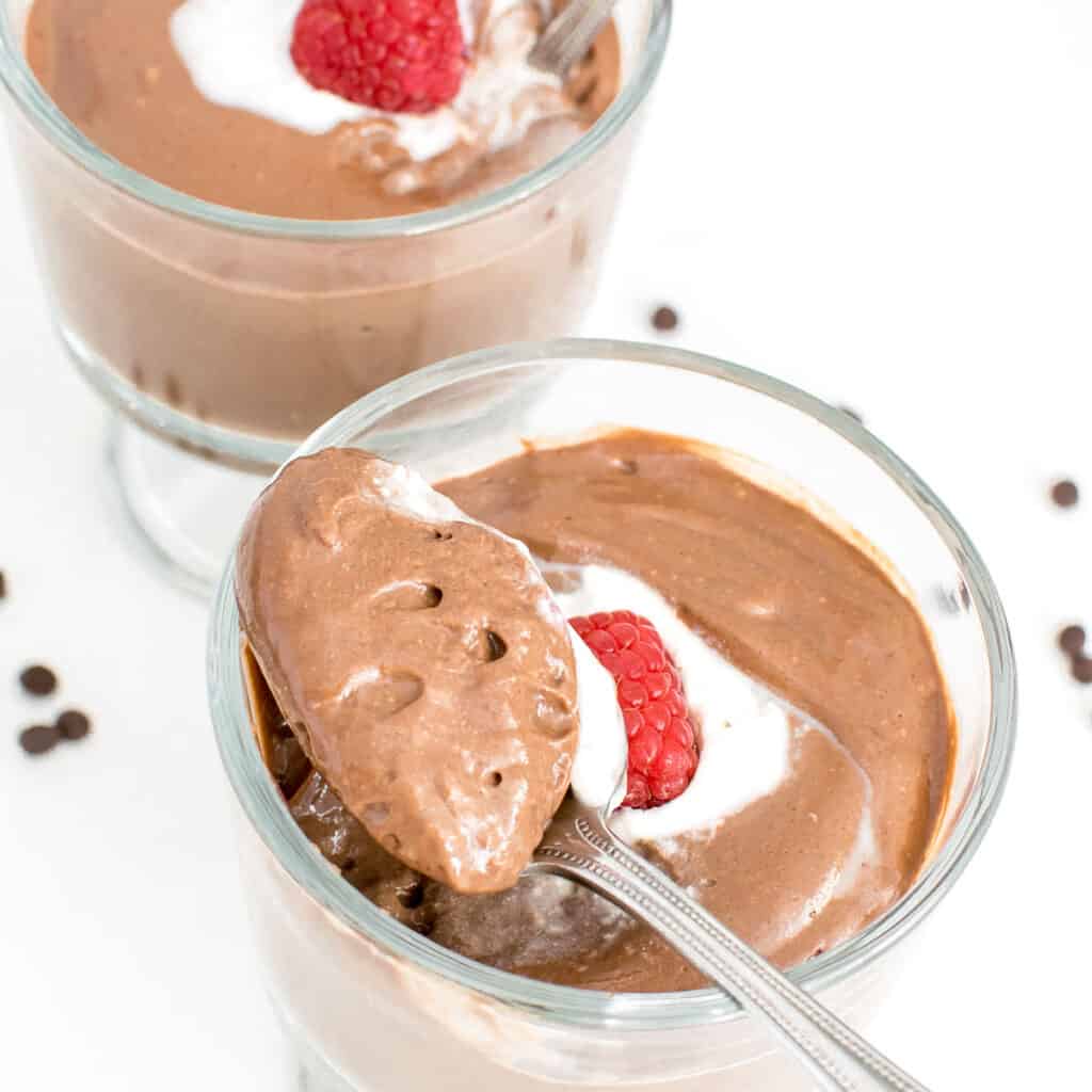 a close up view of vegan chocolate mousse in a spoon. 