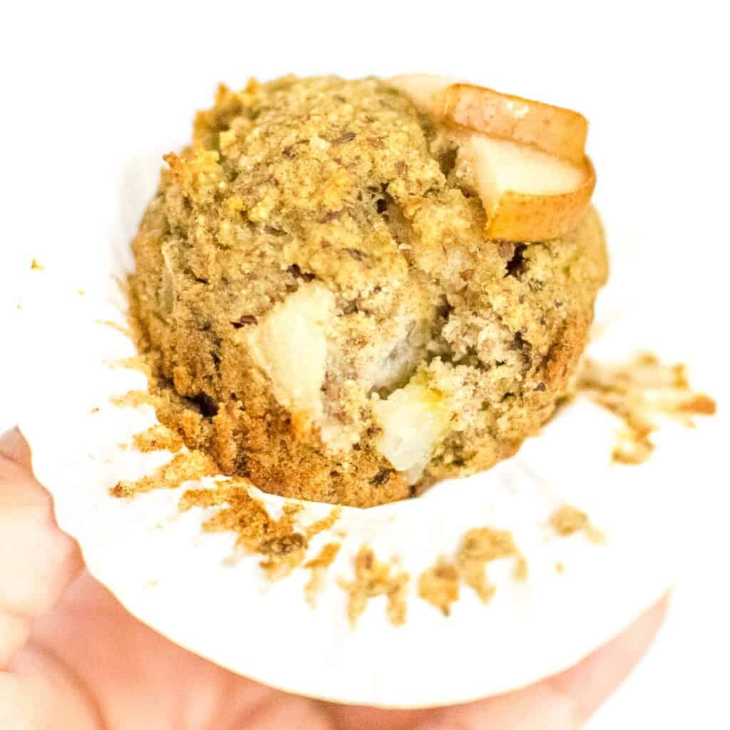 a hand holding pear muffin and showing the inside of it. 