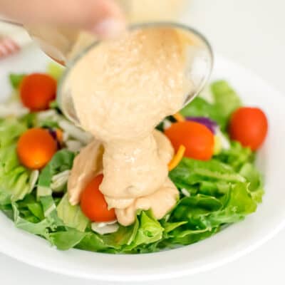 vegan thousand island dressing drizzling over a salad