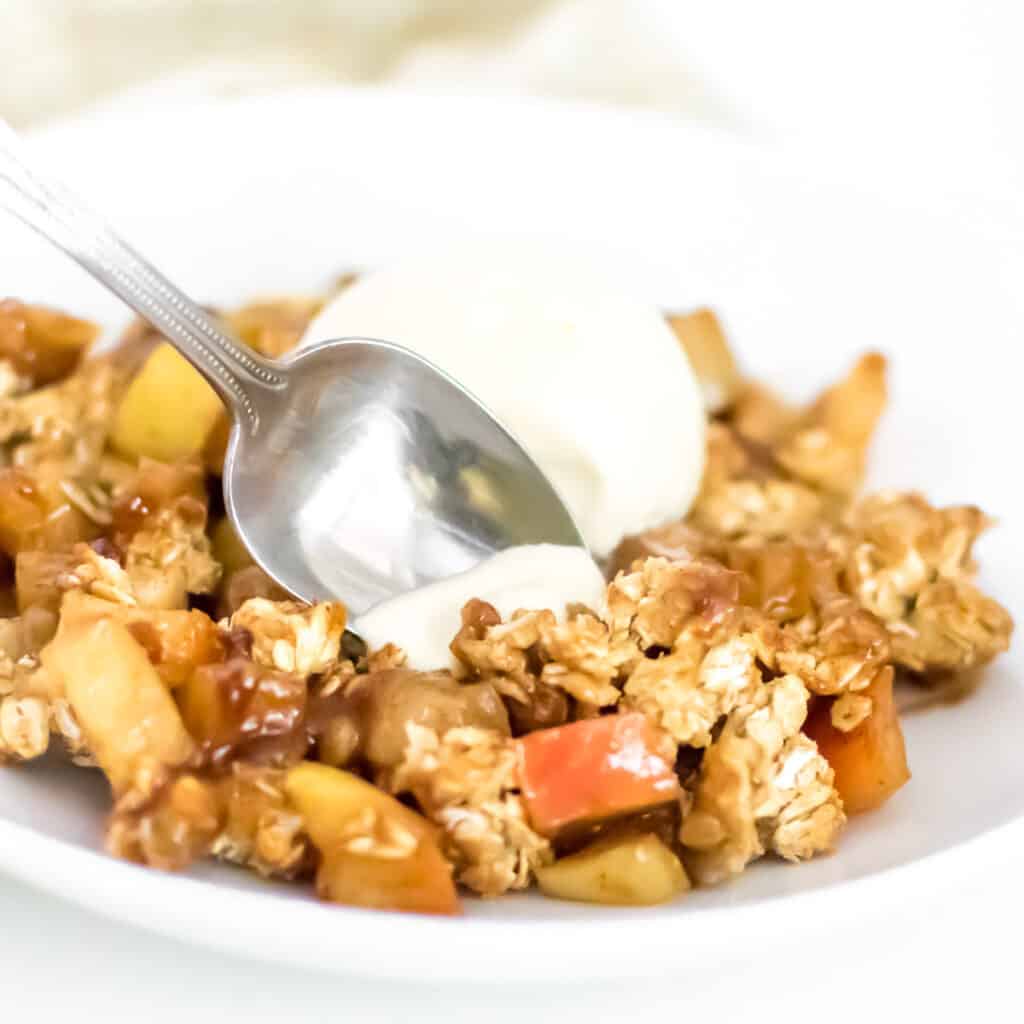 a spoon digging into vegan apple crisp.