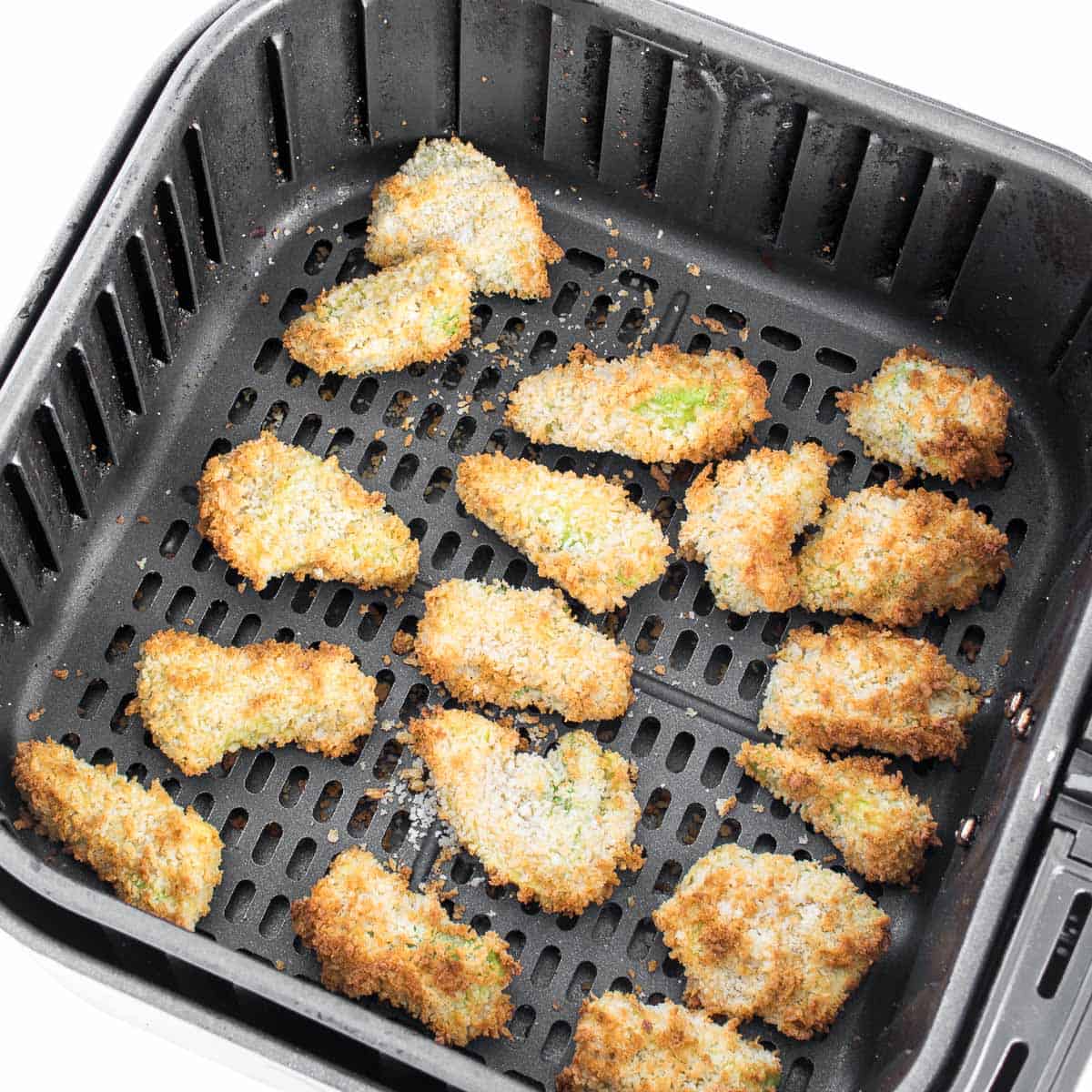 Top view of avocado fries in the air fryer basket.