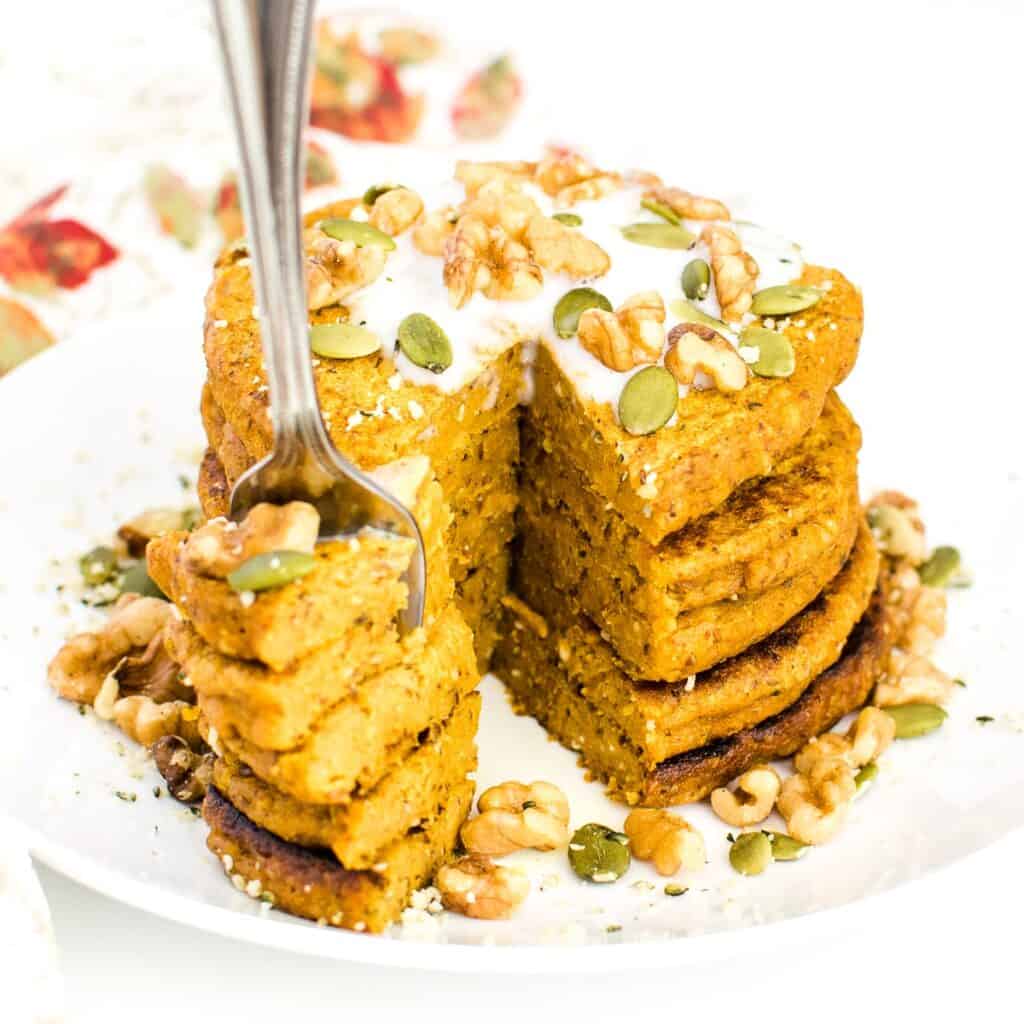 a fork dug into sliced stack of vegan pumpkin pancakes. 