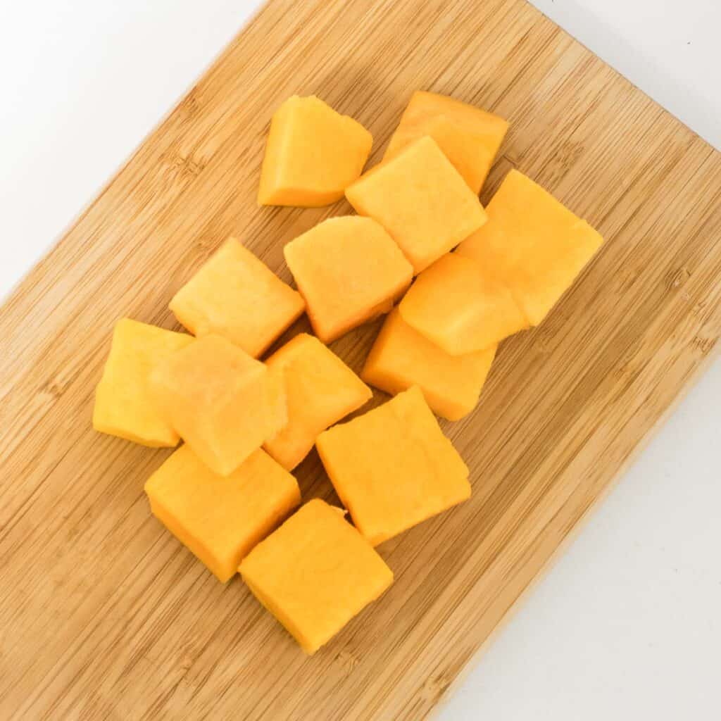 raw butternut squash chopped on a wooden board.