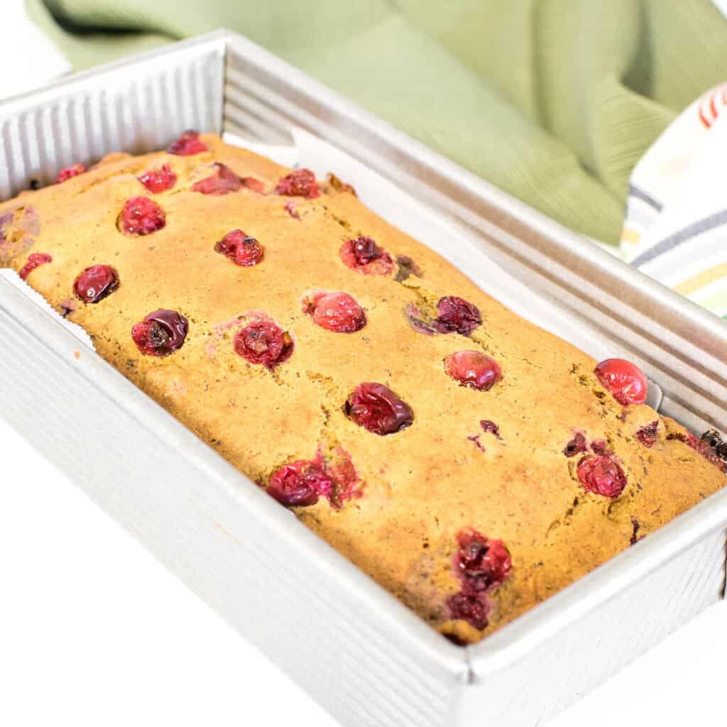 a close up view of vegan cranberry orange bread in the pan cooling down. 