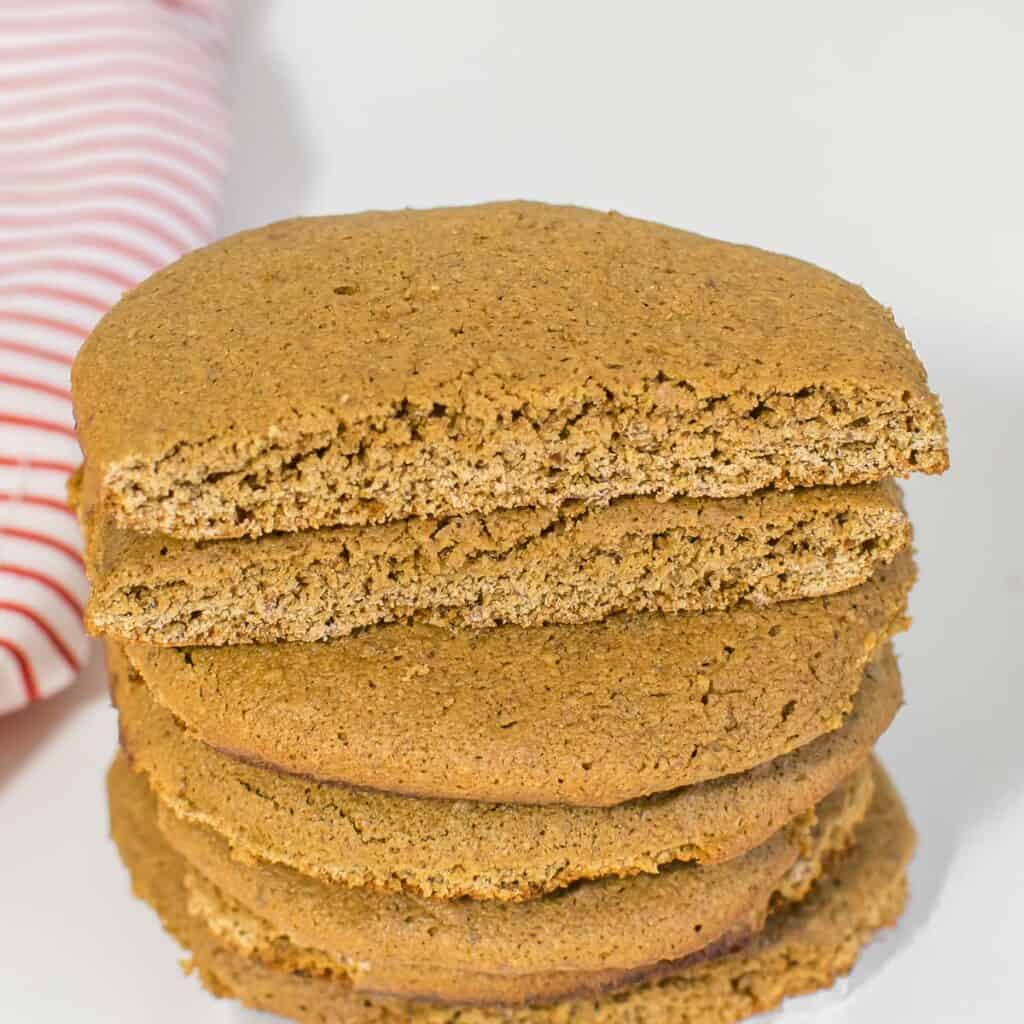 a 45 degree angle view of vegan molasses cookies with a broken one at the top of the stack. 