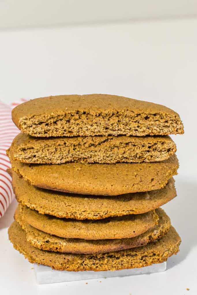 front view of a broken cookie on a stack of vegan ,molasses cookies.