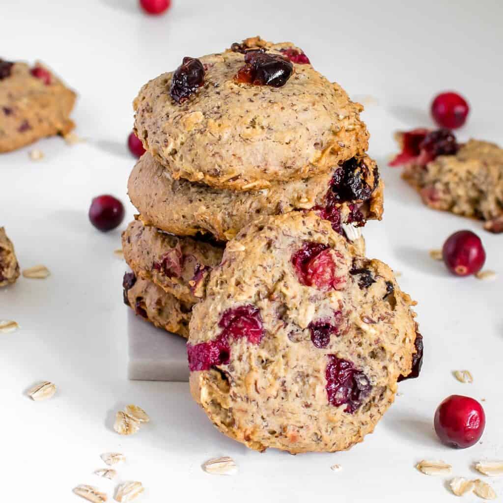one of the vegan oatmeal cranberry cookies in front with a focus supported by its stack.