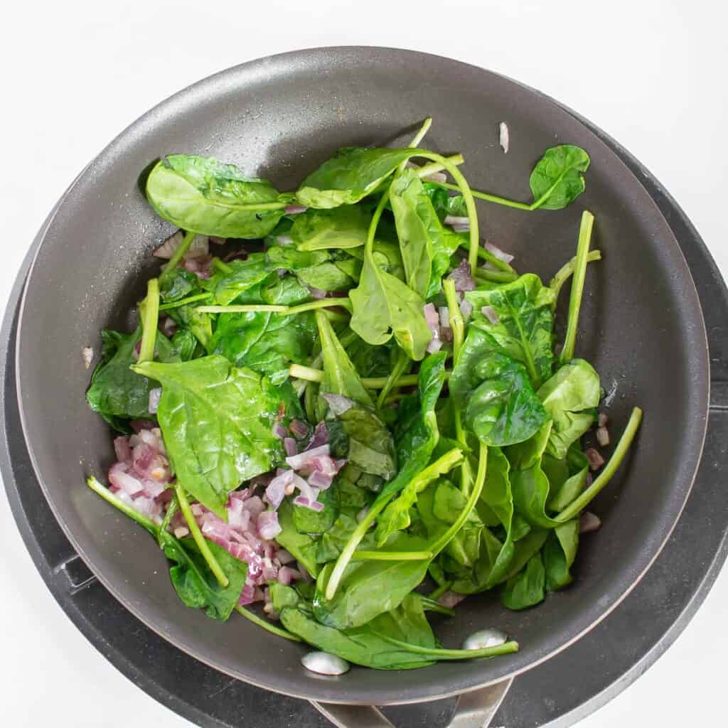 sautéed spinach in the pan along with other ingredients. 