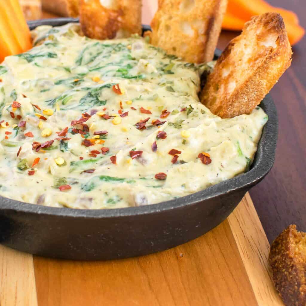 a close up view of served vegan spinach artichoke dip. 