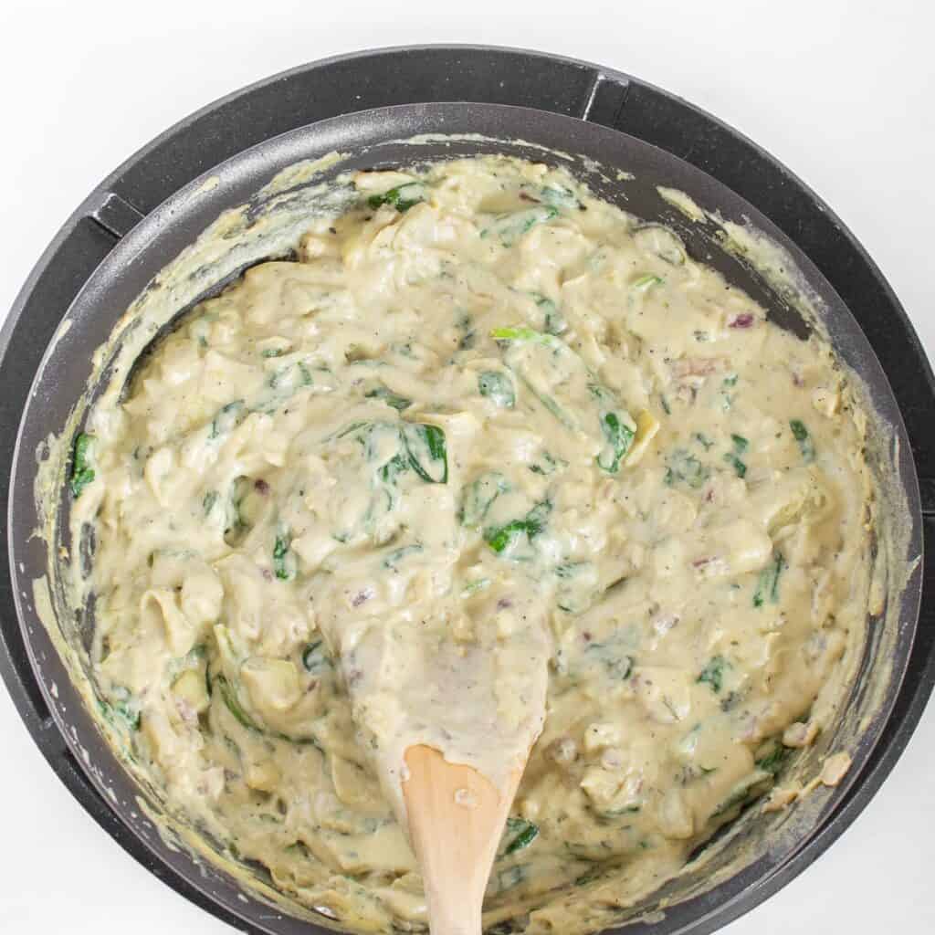 stirred vegan spinach artichoke dip in the pan ready to be served.