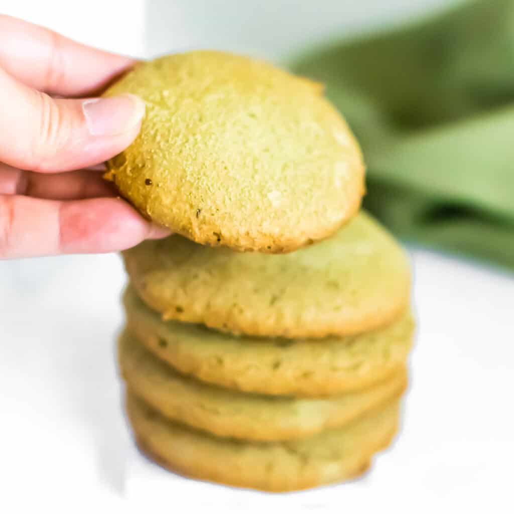 a hand putting stacking matcha cookies.