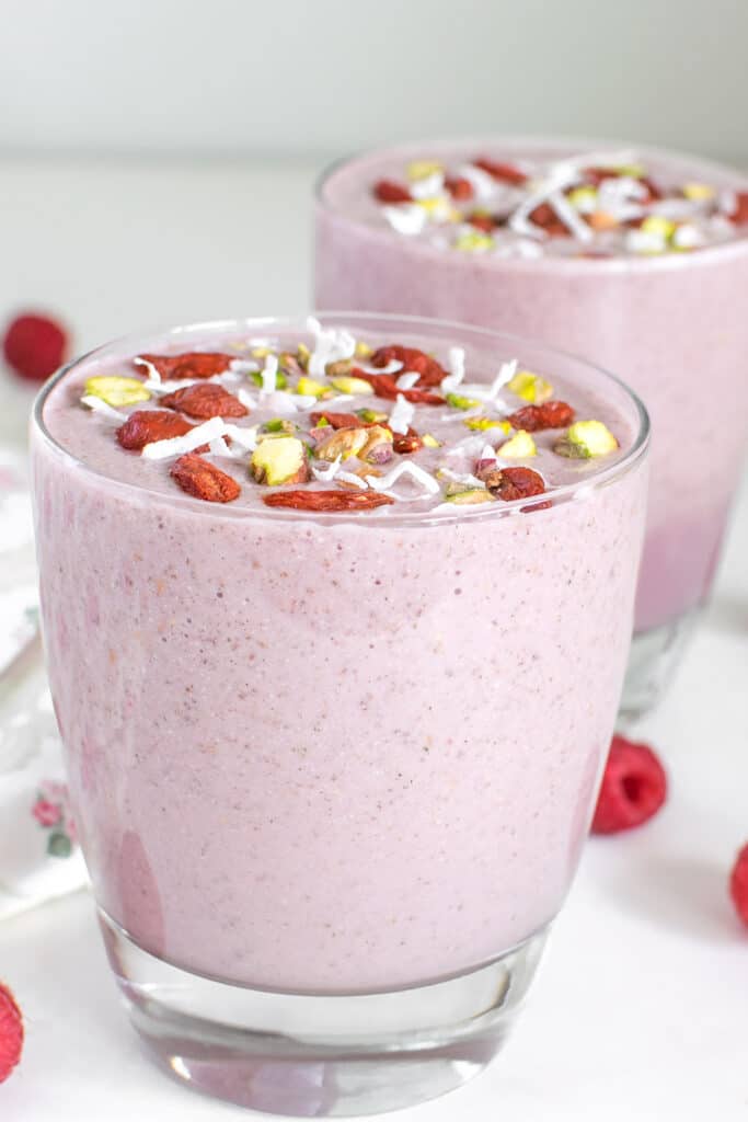 tall glasses served with raspberry smoothie along with its garnishes.