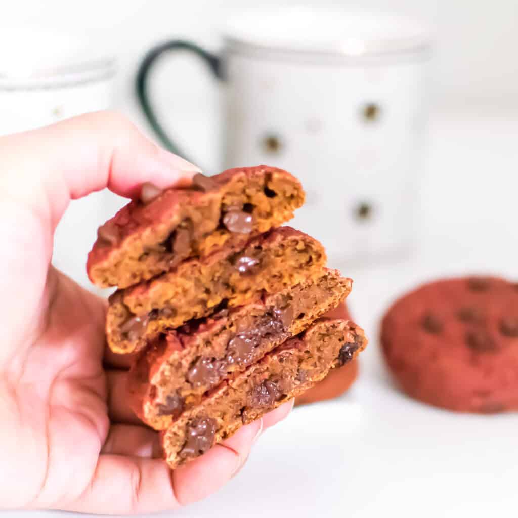 a hand holding stack of broken vegan red velvet cookies. 