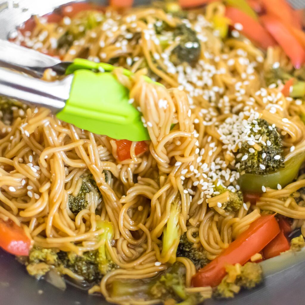 Teriyaki Noodles being picked by the tongs from the wok to be served.