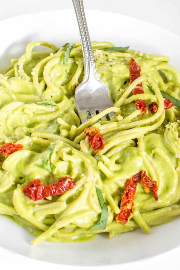 a fork digging into vegan avocado pasta.