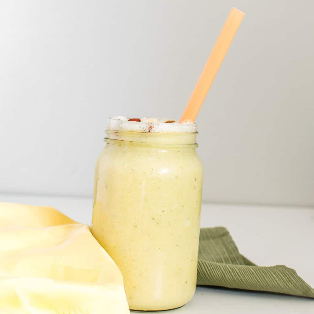 a tall glass of pineapple banana smoothie served.
