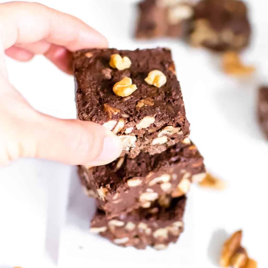 a hand placing a slice of walnut fudge on its stack