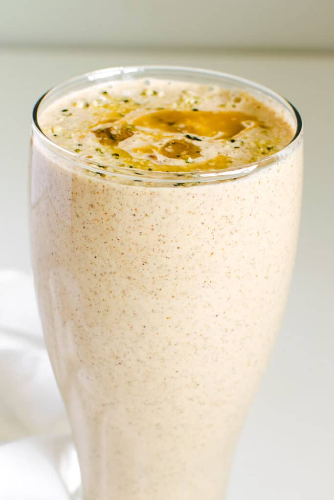 a close up view of banana almond butter smoothie in a serving glass. 
