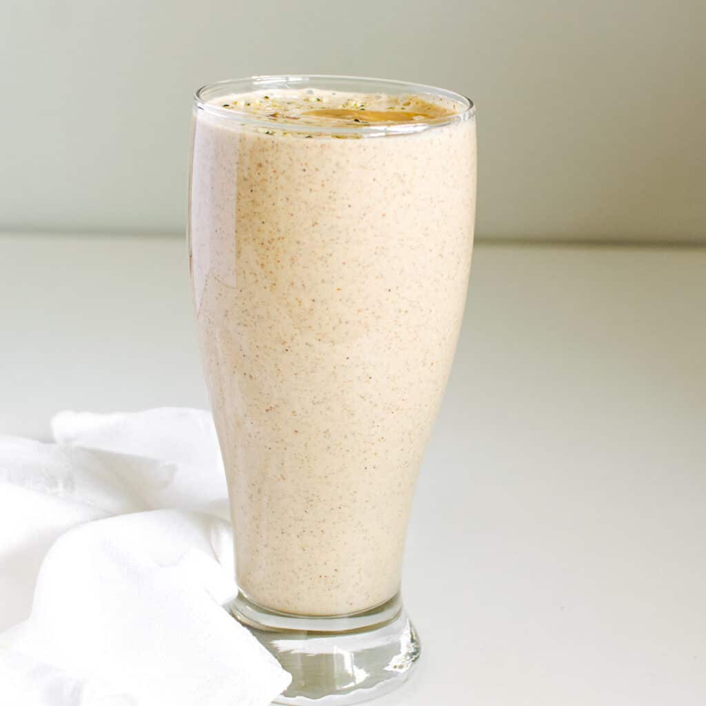 a front view of a tall glass filled with banana almond butter smoothie.