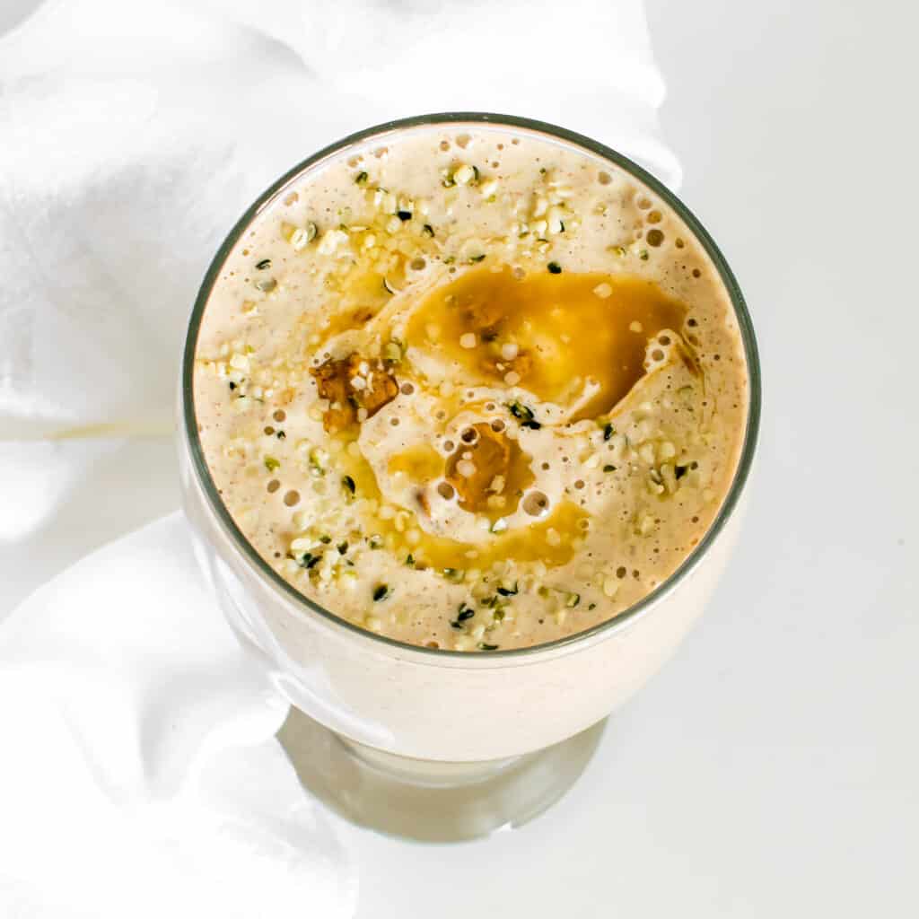 top view of banana almond butter smoothie with garnishes. 