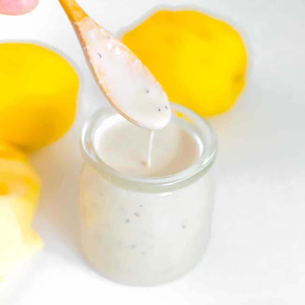 dripping lemon tahini dressing from a spoon into its jar.